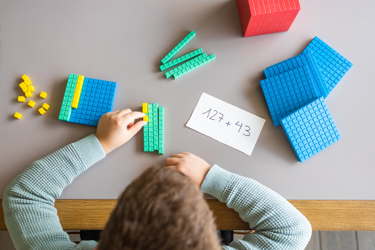 Little Boy Using the Base 10 Method to Do Addition at Home